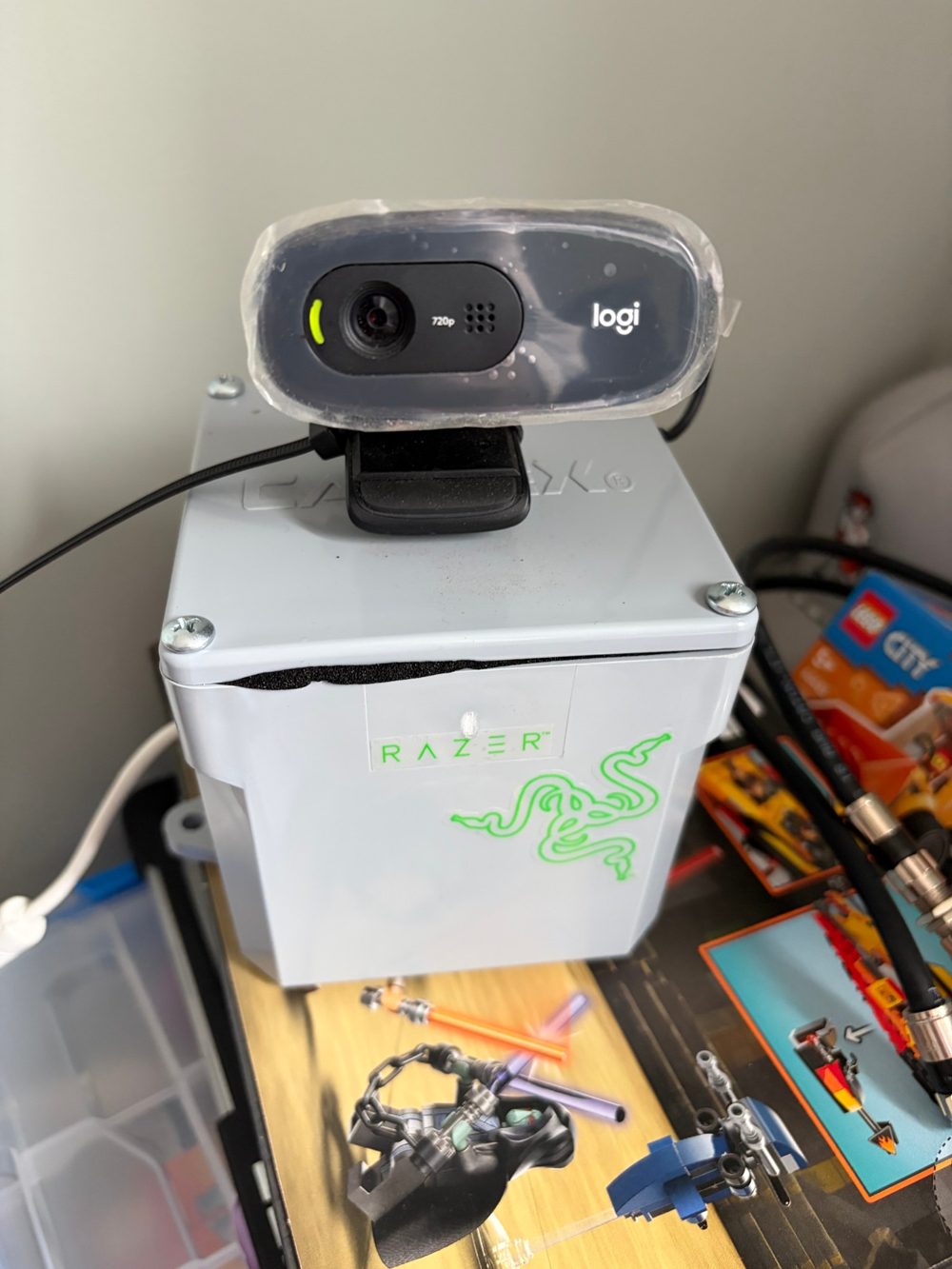 The prototype: a webcam wrapped in clear film, clipped to the lid of a grey PVC junction box.